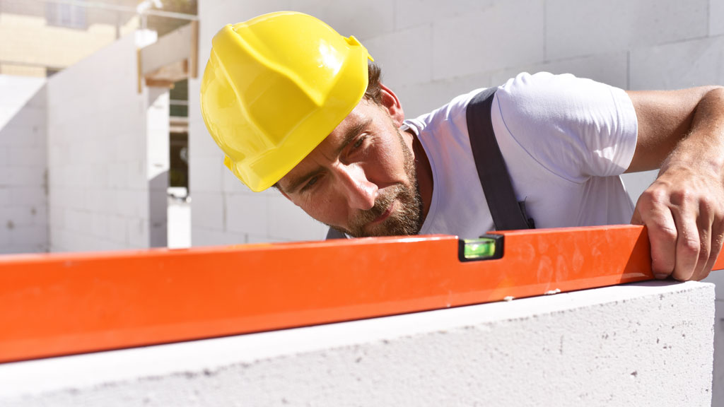 Artisan mesurant un mur intérieur en construction avec mètre laser