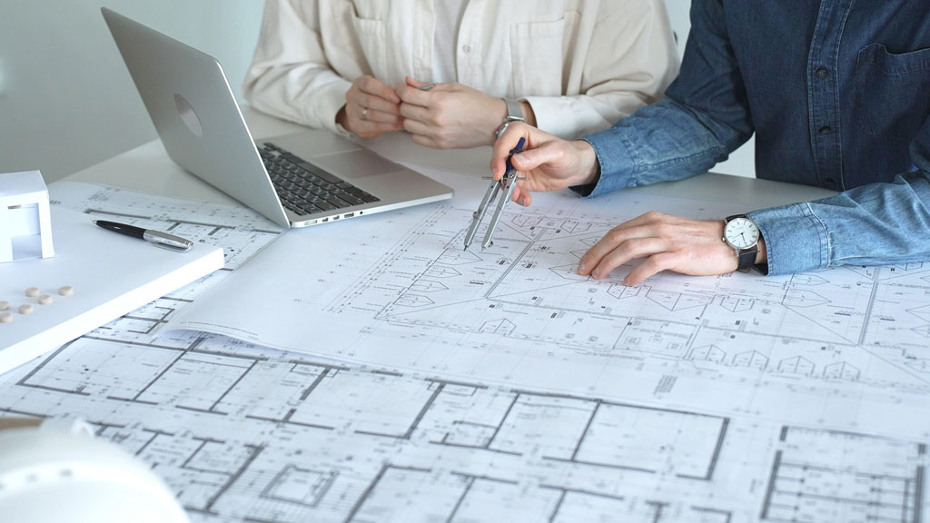 Deux personnes vérifiant des plans de construction sur une table de réunion